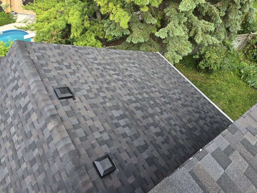 Finished residential asphalt shingle roof with roof vents and clean roofline beside backyard trees by 905 Roofing Inc. in Durham Region and the GTA